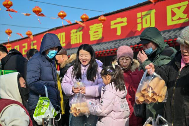 (260126) -- TIANJIN, Jan. 26, 2026 (Xinhua) -- People buy food at  an open air market during the Laba Festival in Tianjin, north China, Jan. 26, 2026. This year's Laba Festival falls on Monday, coinciding with the opening of the Lutai Market in Tianjin. The market features traditional activities such as free distribution of Laba porridge, calligraphy of the character "Fu" for blessings, and a village chef competition, attracting numerous residents from surrounding areas. (Xinhua/Sun Fanyue)