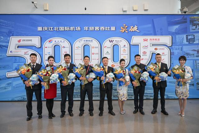 (260126) -- BEIJING, Jan. 26, 2026 (Xinhua) -- Crew members pose for a group photo in front of the commemorative wall marking the annual passenger throughput exceeding 50 million of Chongqing Jiangbei International Airport in Chongqing, southwest China, Dec. 31, 2025. The combined economic output of southwest China's Sichuan Province and Chongqing Municipality has exceeded 10 trillion yuan (about 1.44 trillion U.S. dollar) in 2025, accounting for approximately 7.2 percent of the national total. (Xinhua/Chen Cheng)