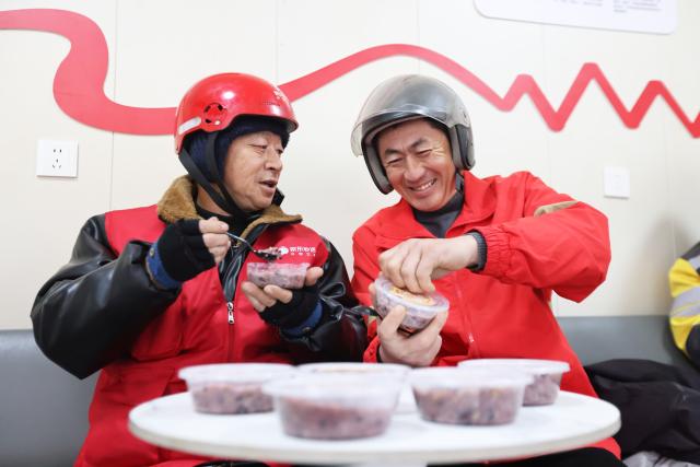 (260126) -- BEIJING, Jan. 26, 2026 (Xinhua) -- Food delivery riders taste Laba porridge presented by community volunteers at a courier station in Huzhou City, east China's Zhejiang Province, Jan. 26, 2026. The Laba Festival, which is celebrated each year on the eighth day of the twelfth lunar month with the custom of having Laba porridge, falls on Monday this year. (Photo by Ni Lifang/Xinhua)