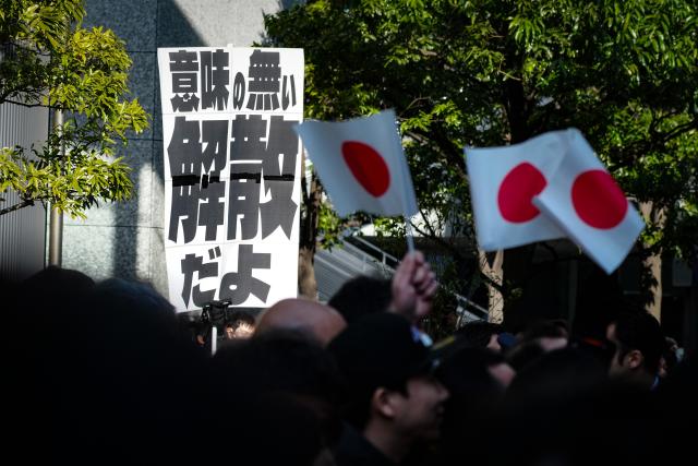 (260127) -- TOKYO, Jan. 27, 2026 (Xinhua) -- A protester holds a sign during a campaign event of Japanese Prime Minister Sanae Takaichi in Tokyo, Japan, on Jan. 27, 2026. Campaigning for Japan's Feb. 8 snap general election officially kicked off across the country on Tuesday with all 465 seats in the House of Representatives up for contest. Of the 465 lower house seats, 289 will be elected from single-member districts and 176 through proportional representation in 11 regional blocs. National broadcaster NHK said more than 1,200 candidates are expected to run. National broadcaster NHK said more than 1,200 candidates are expected to run. (Xinhua/Jia Haocheng)