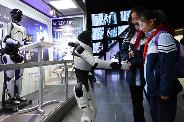 (260127) -- SHANGHAI, Jan. 27, 2026 (Xinhua) -- Visitors shake hands with a robot at the Shanghai Science & Technology Museum in Shanghai, east China, Jan. 27, 2026. The museum launched its operational stress test on Tuesday after more than two years of systematic upgrading, with some visitors and the media being invited to visit. It will commence its trial opening to the public during the Spring Festival. (Xinhua/Fang Zhe)