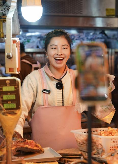 (260127) -- KUNMING, Jan. 27, 2026 (Xinhua) -- A vendor sells chicken via live-streaming at Daguan Zhuanxin farmers' market in Kunming, southwest China's Yunnan Province, Jan. 27, 2026. While preserving the original function of a farmers' market, Daguan Zhuanxin farmers' market has now been upgraded to a complex of cultural experience, dining and entertainment, which offers tourists a window to experience local flavor and vibe. (Xinhua/Chen Xinbo)