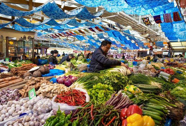 (260127) -- KUNMING, Jan. 27, 2026 (Xinhua) -- A vendor arranges vegetables at Daguan Zhuanxin farmers' market in Kunming, southwest China's Yunnan Province, Jan. 27, 2026. While preserving the original function of a farmers' market, Daguan Zhuanxin farmers' market has now been upgraded to a complex of cultural experience, dining and entertainment, which offers tourists a window to experience local flavor and vibe. (Xinhua/Chen Xinbo)