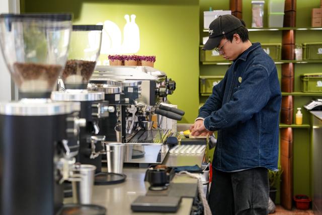 (260127) -- KUNMING, Jan. 27, 2026 (Xinhua) -- A barista makes coffee at Daguan Zhuanxin farmers' market in Kunming, southwest China's Yunnan Province, Jan. 27, 2026. While preserving the original function of a farmers' market, Daguan Zhuanxin farmers' market has now been upgraded to a complex of cultural experience, dining and entertainment, which offers tourists a window to experience local flavor and vibe. (Xinhua/Chen Xinbo)