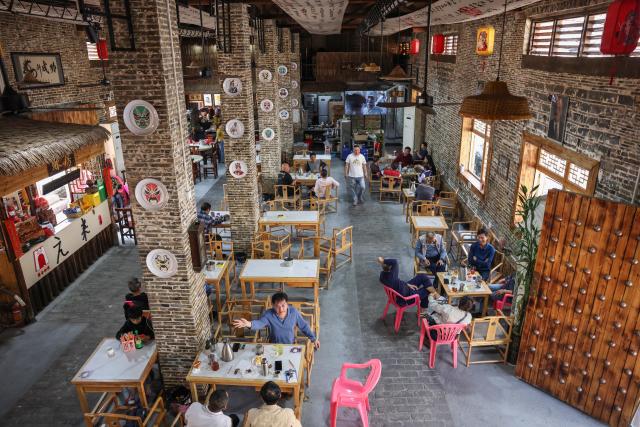 (260128) -- DING'AN, Jan. 28, 2026 (Xinhua) -- People enjoy their leisure time at a coffee shop inside an olden house in Dingcheng Town of Ding'an County, south China's Hainan Province, Jan. 27, 2026.
  Amid China's rural revitalization drive, Ding'an County has been tapping into its own specialty and creativity to boost rural tourism. As a vivid example in developing village-based coffee businesses, the county is now home to 18 distinctive coffee shops, which blend coffee with local culture to create an authentic rustic atmosphere. (Xinhua/Zhang Liyun)