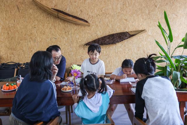 (260128) -- DING'AN, Jan. 28, 2026 (Xinhua) -- Children attend a hands-on painting lecture at a coffee shop in Fuwen Town of Ding'an County, south China's Hainan Province, Jan. 27, 2026.
  Amid China's rural revitalization drive, Ding'an County has been tapping into its own specialty and creativity to boost rural tourism. As a vivid example in developing village-based coffee businesses, the county is now home to 18 distinctive coffee shops, which blend coffee with local culture to create an authentic rustic atmosphere. (Xinhua/Zhang Liyun)