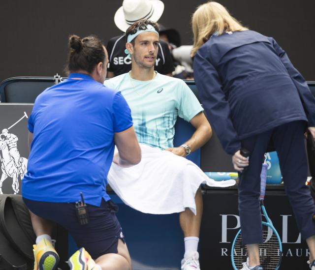 (260128) -- MELBOURNE, Jan. 28, 2026 (Xinhua) -- Lorenzo Musetti (C) of Italy receives medical treatment during the men's singles quarterfinal match between Novak Djokovic of Serbia and Lorenzo Musetti of Italy at the Australian Open tennis tournament in Melbourne, Australia, Jan. 28, 2026. (Photo by Hu Jingchen/Xinhua)