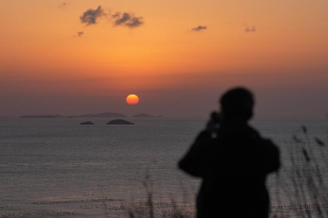 (260128) -- ZHOUSHAN, Jan. 28, 2026 (Xinhua) -- A visitor takes photos of sunset view on the Huaniao island in Shengsi County, Zhoushan City of east China's Zhejiang Province, Jan. 28, 2026. (Xinhua/Huang Zongzhi)
