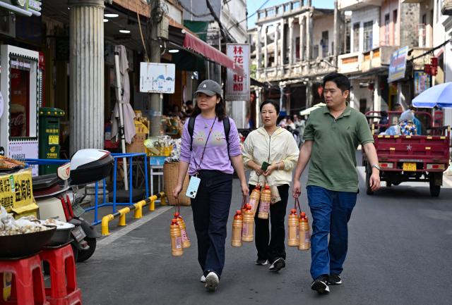 (260201) -- WENCHANG, Feb. 1, 2026 (Xinhua) -- People carry bottles of zaopo vinegar in Puqian Town of Wenchang City, south China's Hainan Province, Jan. 29, 2026. Zaopo vinegar, a traditional specialty of Puqian Town in Wenchang City, has seen industrial growth in recent years as traditional brewing techniques are combined with modern standardized production, helping promote cultural-tourism integration and increase local income. (Xinhua/Guo Cheng)