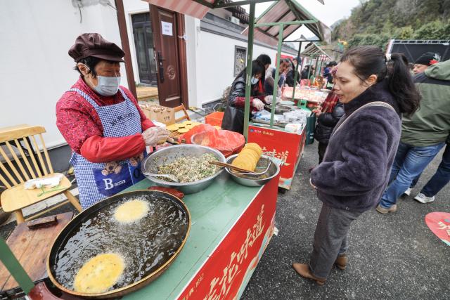 (260201) -- JIANDE, Feb. 1, 2026 (Xinhua) -- A vendor makes local foods at a festive market in Lianhua Township, east China's Zhejiang Province, Feb. 1, 2026. A Spring Festival cultural event was held here with great enthusiasm on Sunday. Local residents and tourists enjoyed the festive market, viewed the local art exhibition, participated in traditional games, and savored local foods. (Xinhua/Xu Yu)
