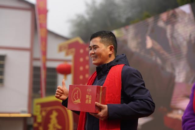 (260201) -- JINGGANGSHAN, Feb. 1, 2026 (Xinhua) -- A villager displays a farm product on a festive gathering held during the Spring Festival gala in Shenshan Village, Jinggangshan City of east China's Jiangxi Province, Feb. 1, 2026. With the Spring Festival drawing near, Shenshan Village in Jinggangshan City held a Spring Festival gala that invited residents from seven nearby counties in east China's Jiangxi and central China's Hunan provinces to participate. (Xinhua/Zhou Mi)