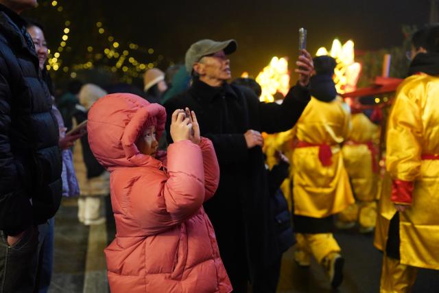 (260201) -- JINGGANGSHAN, Feb. 1, 2026 (Xinhua) -- A child watches a wooden-bench dragon dance during the Spring Festival gala held in Shenshan Village, Jinggangshan City of east China's Jiangxi Province, Jan. 31, 2026. With the Spring Festival drawing near, Shenshan Village in Jinggangshan City held a Spring Festival gala that invited residents from seven nearby counties in east China's Jiangxi and central China's Hunan provinces to participate. (Xinhua/Zhou Mi)