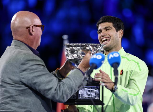 (260201) -- MELBOURNE, Feb. 1, 2026 (Xinhua) -- Carlos Alcaraz (R) receives the trophy at the awarding ceremony after winning the men's singles final between Carlos Alcaraz of Spain and Novak Djokovic of Serbia at the Australian Open tennis tournament in Melbourne, Australia, Feb. 1, 2026. (Xinhua/Ma Ping)