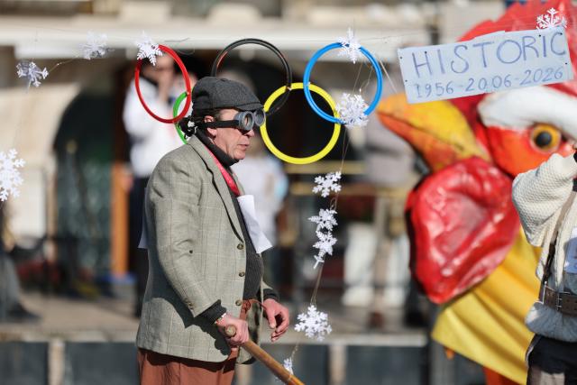 (260202) -- VENICE, Feb. 2, 2026 (Xinhua) -- A reveler displays a board written the year of the three Winter Olympic Games that held in Italy, during the water parade of Venice Carnival in Venice, Italy, Feb. 1, 2026. The 2026 version of the traditional Venice Carnival runs from Jan. 31 to Feb. 17. (Xinhua/Li Jing)
