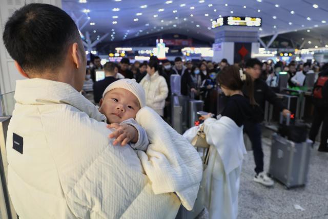 (260202) -- BEIJING, Feb. 2, 2026 (Xinhua) -- A man holding an infant is pictured at Shenzhen North Railway Station in Shenzhen, south China's Guangdong Province, Feb. 2, 2026. China ushered in its largest annual population migration on Monday, 15 days ahead of the 2026 Spring Festival, also known as the Chinese New Year.
  A total of 9.5 billion passenger trips are expected during this year's travel rush period that will end on March 13, which will be a historic high.
  Of this total, road trips remain the dominant mode of travel, accounting for approximately 80 percent. 
  An estimated 540 million passenger trips will be handled by the country's railways, while the civil aviation sector will see 95 million trips. Both the overall scale and daily peak traffic of rail and air travel are expected to surpass historic high levels this year.
  In China, the 40-day travel surge will witness hundreds of millions of people return to their hometowns for family reunions. (Xinhua/Mao Siqian)