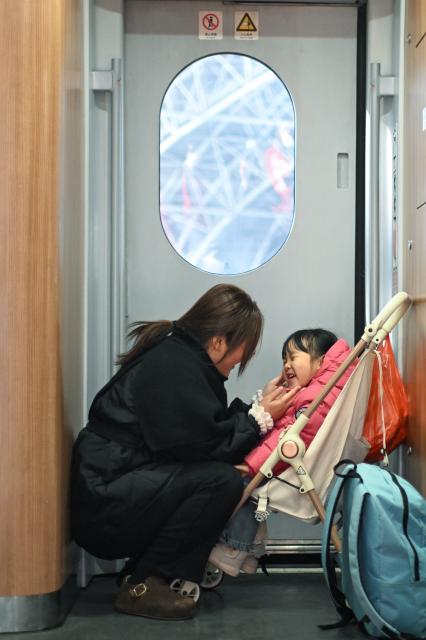 (260202) -- BEIJING, Feb. 2, 2026 (Xinhua) -- A woman interacts with a child aboard a train at Kunshan South Railway Station in Kunshan City, east China's Jiangsu Province, Feb. 2, 2026.
  China ushered in its largest annual population migration on Monday, 15 days ahead of the 2026 Spring Festival, also known as the Chinese New Year.
  A total of 9.5 billion passenger trips are expected during this year's travel rush period that will end on March 13, which will be a historic high.
  In China, the 40-day travel surge will witness hundreds of millions of people return to their hometowns for family reunions. (Photo by Wang Xuzhong/Xinhua)