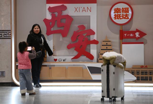 (260202) -- BEIJING, Feb. 2, 2026 (Xinhua) -- A woman poses for a photo in front of an installation at the departure hall of Xi'an Railway Station in Xi'an, northwest China's Shaanxi Province, Feb. 2, 2026. China ushered in its largest annual population migration on Monday, 15 days ahead of the 2026 Spring Festival, also known as the Chinese New Year.
  A total of 9.5 billion passenger trips are expected during this year's travel rush period that will end on March 13, which will be a historic high.
  Of this total, road trips remain the dominant mode of travel, accounting for approximately 80 percent. 
  An estimated 540 million passenger trips will be handled by the country's railways, while the civil aviation sector will see 95 million trips. Both the overall scale and daily peak traffic of rail and air travel are expected to surpass historic high levels this year.
  In China, the 40-day travel surge will witness hundreds of millions of people return to their hometowns for family reunions. (Xinhua/Li Yibo)