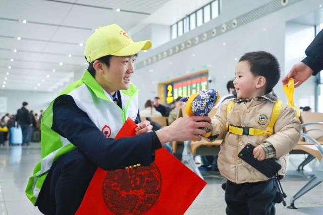 (260202) -- BEIJING, Feb. 2, 2026 (Xinhua) -- A volunteer interacts with a child at Sanming North Railway Station in Sanming, southeast China's Fujian Province, Feb. 2, 2026. China ushered in its largest annual population migration on Monday, 15 days ahead of the 2026 Spring Festival, also known as the Chinese New Year.
  A total of 9.5 billion passenger trips are expected during this year's travel rush period that will end on March 13, which will be a historic high.
  Of this total, road trips remain the dominant mode of travel, accounting for approximately 80 percent. 
  An estimated 540 million passenger trips will be handled by the country's railways, while the civil aviation sector will see 95 million trips. Both the overall scale and daily peak traffic of rail and air travel are expected to surpass historic high levels this year.
  In China, the 40-day travel surge will witness hundreds of millions of people return to their hometowns for family reunions. (Photo by Yan Tan/Xinhua)
