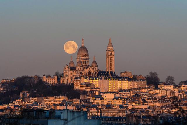 (260202) -- PARIS, Feb. 2, 2026 (Xinhua) -- A full snow moon is seen next to the Sacre Coeur Basilica at sunrise in Montmartre, Paris, France, Feb. 2, 2026. (Photo by Aurelien Morissard/Xinhua)