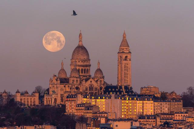 (260202) -- PARIS, Feb. 2, 2026 (Xinhua) -- A full snow moon is seen next to the Sacre Coeur Basilica at sunrise in Montmartre, Paris, France, Feb. 2, 2026. (Photo by Aurelien Morissard/Xinhua)