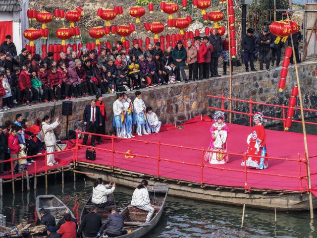 (260202) -- HANGZHOU, Feb. 2, 2026 (Xinhua) -- A drone photo shows villagers watching a traditional water-town opera performance at Mojiaqiao Village in Hangzhou, east China's Zhejiang Province, Feb. 2, 2026. As the Chinese New Year approaches, Mojiaqiao Village in Hangzhou City has held a series of festive activities, recreating traditional Chinese New Year customs of a water town and creating a joyful atmosphere for the upcoming holiday. (Xinhua/Xu Yu)