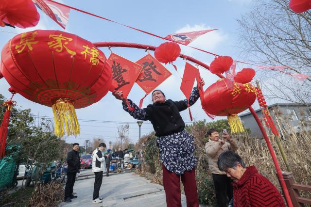 (260202) -- HANGZHOU, Feb. 2, 2026 (Xinhua) -- A villager decorates with lanterns and festive ornaments at Mojiaqiao Village in Hangzhou, east China's Zhejiang Province, Feb. 2, 2026. As the Chinese New Year approaches, Mojiaqiao Village in Hangzhou City has held a series of festive activities, recreating traditional Chinese New Year customs of a water town and creating a joyful atmosphere for the upcoming holiday. (Xinhua/Xu Yu)