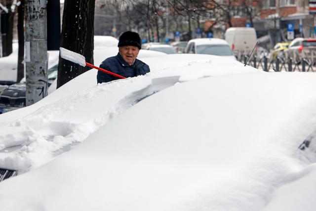 (260202) -- BUCHAREST, Feb. 2, 2026 (Xinhua) -- A man cleans his snow-covered car in Bucharest, Romania, on Feb. 2, 2026. Romania's National Meteorological Administration (ANM) on Monday issued a Code Yellow warning for severe cold and frost, affecting more than half of the country, from Monday morning until Tuesday. (Photo by Cristian Cristel/Xinhua)