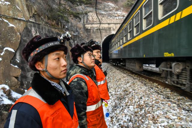 (260204) -- JINZHONG, Feb. 4, 2026 (Xinhua) -- Members of a maintenance squad wait as a train runs past in north China's Shanxi Province, Feb. 3, 2026.
  A team of maintenance technicians, most born in the 2000s, has spent the winter months shoveling and removing ice from railway tunnels deep in the mountainous terrain in Shanxi province to safeguard passengers' trips.
  Embarking on the patrol journey at dawn, they trek more than nine kilometers every day to clear ice in seven railway tunnels. The arduous chipping, shoveling and transporting of large ice chucks means the technicians are totally burned out after a day of work.
  During the Chinese New Year, the team will stay on duty to ensure the safe operation of train services. Through their efforts, thousands more who have been working far from their hometowns for almost a year will be able to ride the train and return home safe and sound. (Xinhua/Cao Yang)