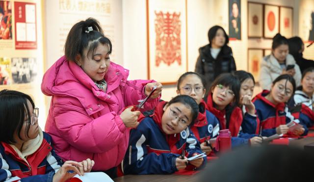 (260204) -- HOHHOT, Feb. 4, 2026 (Xinhua) -- Niu Chunxia (2nd L), a representative inheritor of Horinger paper-cutting, displays paper-cutting skills for students at an exhibition hall of the Horinger Tuchengzi Archaeological Site Park in Horinger County, north China's Inner Mongolia Autonomous Region, Feb. 4, 2026. Events featuring the traditional craft of Horinger paper-cutting, a national intangible cultural heritage, were held in Horinger County on Wednesday to mark "Lichun," or the Beginning of Spring, the first of the 24 solar terms on the Chinese lunar calendar, and to welcome the upcoming Spring Festival. (Xinhua/Bei He)