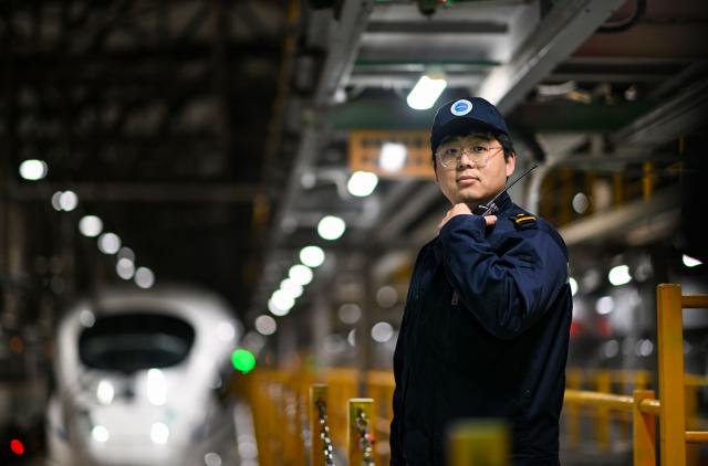 (260204) -- TIANJIN, Feb. 4, 2026 (Xinhua) -- Li Qiwei communicates with his colleagues via walkie-talkie at an electric multiple unit (EMU) maintenance depot in north China's Tianjin Municipality, on Feb. 1, 2026. Several EMU trains are neatly lined up for "health checkups" inside a maintenance depot in Tianjin at the night of Feb. 1, right before the start of Spring Festival travel rush, the annual homeward journey in China, and also the world's largest human migration. 
   To ensure safe and punctual departure of these trains, Li Qiwei, the leader of a maintenance team, had to work overnight with more than 40 mates on his team to perform full-body examination for 28 sets of EMUs - a workload about 20 percent higher than that of a normal workday.
   Li has been working at the maintenance depot after he graduated with a degree in vehicle engineering from the Dalian Jiaotong University. Eight years of diligence saw him rising from green hands to a competent group leader. He said he felt very lucky to be able to contribute to the safety operation of the bullet trains, which are reuniting million of people with their families during the Spring Festival travel rush. (Xinhua/Zhao Zishuo)