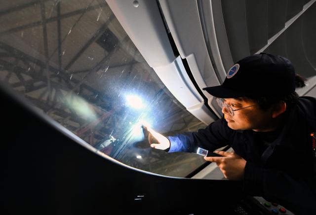 (260204) -- TIANJIN, Feb. 4, 2026 (Xinhua) -- Li Qiwei checks the wiper blades of the train at an electric multiple unit (EMU) maintenance depot in north China's Tianjin Municipality, on Feb. 2, 2026. Several EMU trains are neatly lined up for "health checkups" inside a maintenance depot in Tianjin at the night of Feb. 1, right before the start of Spring Festival travel rush, the annual homeward journey in China, and also the world's largest human migration. 
   To ensure safe and punctual departure of these trains, Li Qiwei, the leader of a maintenance team, had to work overnight with more than 40 mates on his team to perform full-body examination for 28 sets of EMUs - a workload about 20 percent higher than that of a normal workday.
   Li has been working at the maintenance depot after he graduated with a degree in vehicle engineering from the Dalian Jiaotong University. Eight years of diligence saw him rising from green hands to a competent group leader. He said he felt very lucky to be able to contribute to the safety operation of the bullet trains, which are reuniting million of people with their families during the Spring Festival travel rush. (Xinhua/Zhao Zishuo)