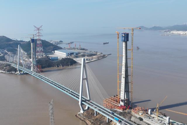 (260204) -- ZHOUSHAN, Feb. 4, 2026 (Xinhua) -- An aerial drone photo taken on Feb. 4, 2026 shows the Taoyaomen highway-railway bridge (R) under construction in Zhoushan, east China's Zhejiang Province. The No. 6 main tower of the Taoyaomen highway-railway bridge, constructed by the China Railway Major Bridge Engineering Group Co., Ltd., was topped out on Wednesday, marking a significant breakthrough of this project. (Xinhua/Huang Zongzhi)