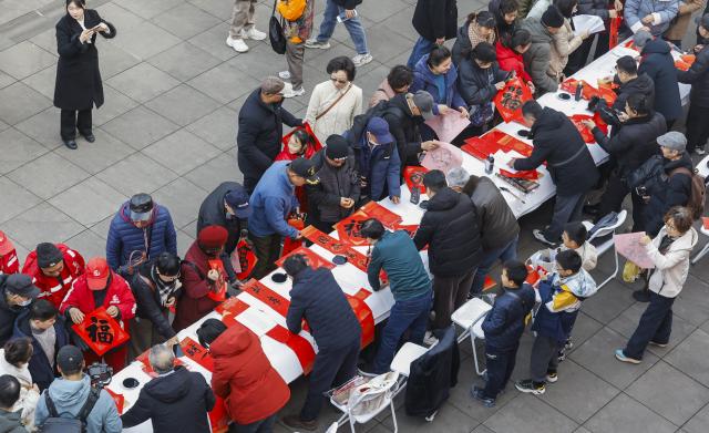 (260204) -- BEIJING, Feb. 4, 2026 (Xinhua) -- Calligraphers write the character "Fu", which means good fortune, and Spring Festival couplets for citizens and tourists on the occasion of "Lichun" in Gulou District of Nanjing, east China's Jiangsu Province, on Feb. 4, 2026. Wednesday marks "Lichun," or the Beginning of Spring, the first of the 24 solar terms on the Chinese lunar calendar. (Photo by Zhao Qirui/Xinhua)