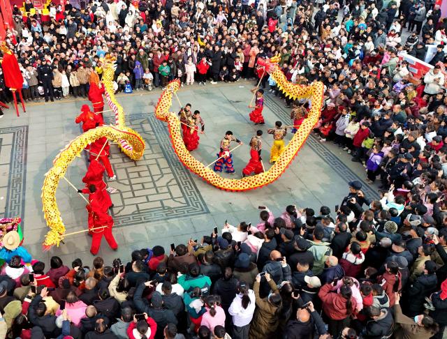 (260204) -- BEIJING, Feb. 4, 2026 (Xinhua) -- An aerial drone photo taken on Feb. 4, 2026 shows people watching a dragon dance on the occasion of "Lichun" in Nanyang, central China's Henan Province. Wednesday marks "Lichun," or the Beginning of Spring, the first of the 24 solar terms on the Chinese lunar calendar. (Photo by Gao Song/Xinhua)