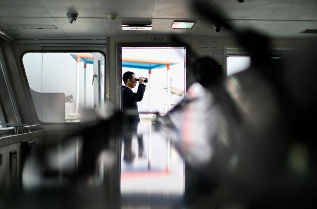 (260205) -- TIANJIN, Feb. 5, 2026 (Xinhua) -- Xu Qinping checks the navigation channel through a telescope on a cargo ferry at Tianjin Port in Tianjin, north China, Feb. 4, 2026.
  Sun Bo and Xu Qinping are both port pilots at Tianjin Port. A port pilot needs to be familiar not only with the port's navigation conditions, but also with vessel maneuvering skills. Working around the clock across navigation channels, berthing locations and anchorage grounds, they are responsible for the safe arrival and departure of ships at the port. 
  "When guiding the anchoring of a vessel weighing hundreds of thousands of tons, we must maneuver with centimeter-level precision," said Sun Bo. According to him, the most dangerous part is embarking from the anchorage, when a pilot must choose the right moment to climb up a soft ladder. A single moment of carelessness could lead to a fall into the sea. Moreover, port pilots work year-round without breaks, with the daily ship schedule dictating their routine. 
  Over his 22-year career, Sun Bo has piloted more than 4,500 vessels and also witnessed the rapid development of China's ports and foreign trade. (Xinhua/Zhao Zishuo)