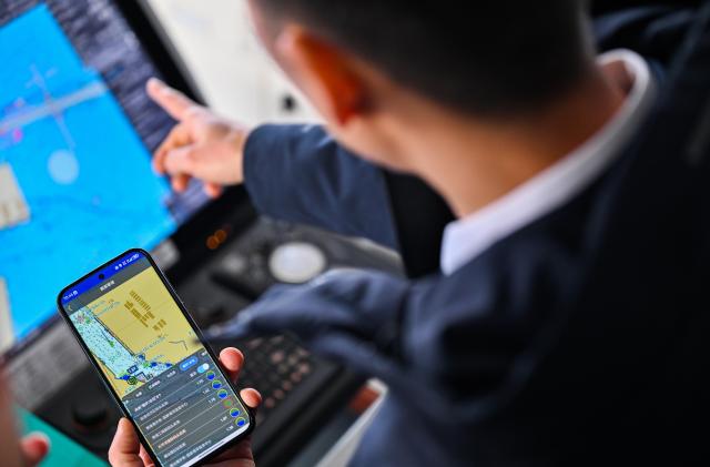 (260205) -- TIANJIN, Feb. 5, 2026 (Xinhua) -- Xu Qinping checks the movement of a cargo ferry through his cellphone at Tianjin Port in Tianjin, north China, Feb. 4, 2026.
  Sun Bo and Xu Qinping are both port pilots at Tianjin Port. A port pilot needs to be familiar not only with the port's navigation conditions, but also with vessel maneuvering skills. Working around the clock across navigation channels, berthing locations and anchorage grounds, they are responsible for the safe arrival and departure of ships at the port. 
  "When guiding the anchoring of a vessel weighing hundreds of thousands of tons, we must maneuver with centimeter-level precision," said Sun Bo. According to him, the most dangerous part is embarking from the anchorage, when a pilot must choose the right moment to climb up a soft ladder. A single moment of carelessness could lead to a fall into the sea. Moreover, port pilots work year-round without breaks, with the daily ship schedule dictating their routine. 
  Over his 22-year career, Sun Bo has piloted more than 4,500 vessels and also witnessed the rapid development of China's ports and foreign trade. (Xinhua/Zhao Zishuo)