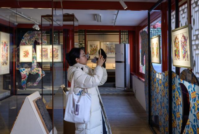 (260205) -- BEIJING, Feb. 5, 2026 (Xinhua) -- A tourist takes photos of an exhibit during a Chinese New Year paintings exhibition at Prince Kung's Palace Museum in Beijing, capital of China, Feb. 4, 2026. An exhibition displaying more than a hundred exquisite Chinese New Year paintings collected by Prince Kung's Palace Museum opened here on Wednesday. (Xinhua/Jin Liangkuai)