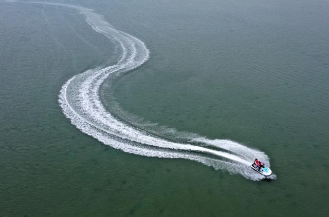 (260205) -- BEIHAI, Feb. 5, 2026 (Xinhua) -- An aerial drone photo taken on Feb. 5, 2026 shows tourists enjoying water activities in the sea near Beihai City, south China's Guangxi Zhuang Autonomous Region. (Xinhua/Lu Boan)