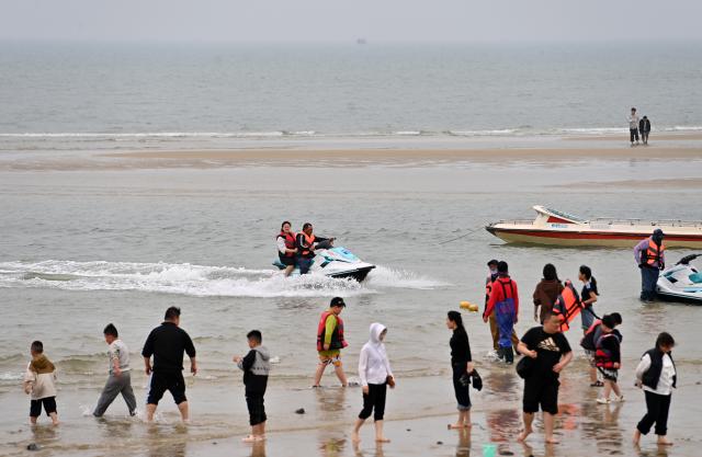 (260205) -- BEIHAI, Feb. 5, 2026 (Xinhua) -- Tourists enjoy water activities in the sea near Beihai City, south China's Guangxi Zhuang Autonomous Region, Feb. 5, 2026. (Xinhua/Lu Boan)