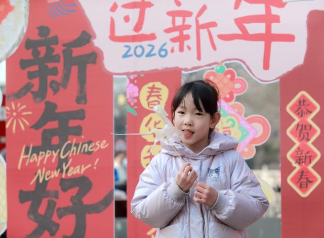 (260205) -- BEIJING, Feb. 5, 2026 (Xinhua) -- A child tastes a syrup figurine at a fair featuring Chinese New Year goods in Yangzhou City, east China's Jiangsu Province, Feb. 4, 2026. Fairs and events are held across the country, where people shop for goods in preparation for the upcoming Spring Festival, or the Chinese New Year. (Photo by Meng Delong/Xinhua)
