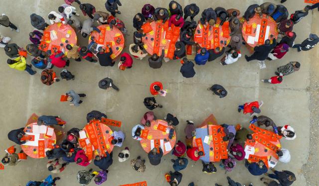 (260205) -- BEIJING, Feb. 5, 2026 (Xinhua) -- An aerial drone photo taken on Feb. 4, 2026 shows calligrapher writing couplets and Chinese character "Fu" (meaning good fortune) for people at a farmers' market in Jinglou Town of Zhangshu City, east China's Jiangxi Province. Fairs and events are held across the country, where people shop for goods in preparation for the upcoming Spring Festival, or the Chinese New Year. (Photo by Zhou Liang/Xinhua)