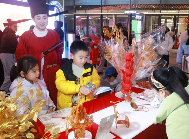 (260205) -- WUHAN, Feb. 5, 2026 (Xinhua) -- Children try their hands with syrup art at an event themed on the "Hubei New Spring International Consumption Season" in Wuhan, central China's Hubei Province, Feb. 5, 2026. The "Hubei New Spring International Consumption Season" kicked off here on Thursday, attempting to create diverse consumption scenarios for the upcoming Spring Festival. (Photo by Zhao Jun/Xinhua)