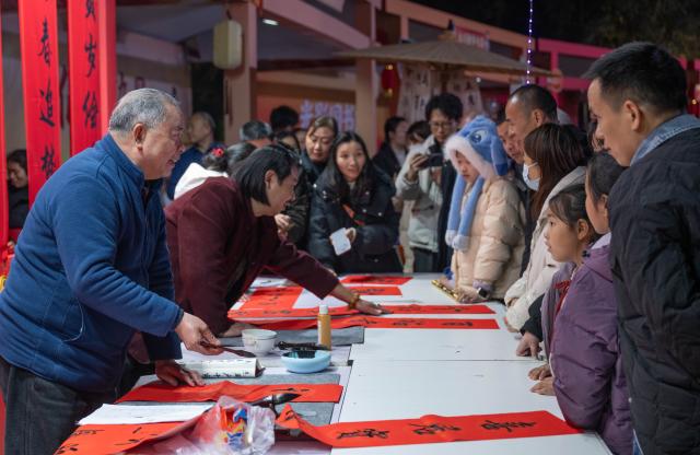 (260206) -- CHONGQING, Feb. 6, 2026 (Xinhua) -- Artists write spring couplets for citizens at a park in southwest China's Chongqing Municipality, Feb. 5, 2026. A fair featuring Chinese New Year goods kicked off here on Thursday, offering residents a one-stop destination for New Year shopping with diverse choices. (Xinhua/Chen Cheng)