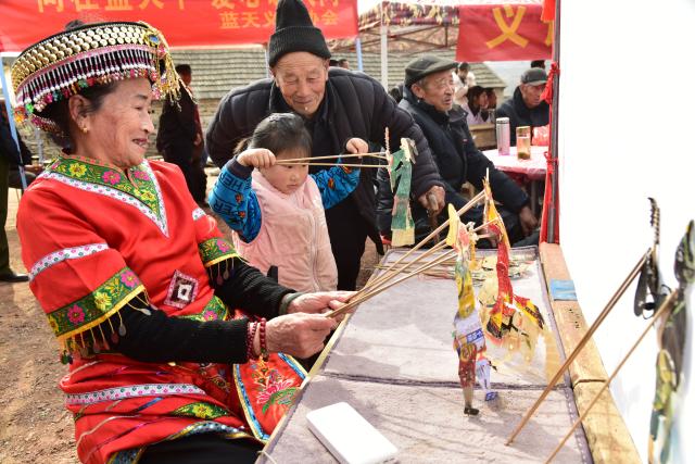 (260206) -- BEIJING, Feb. 6, 2026 (Xinhua) -- A girl learns to play shadow puppet from a folk artist during a village gala held in Chaishanqian Village, Zaozhuang City of east China's Shandong Province, Feb. 5, 2026. With the Spring Festival drawing near, various festive events are held across the country to celebrate the Chinese New Year. (Photo by Liu Mingxiang/Xinhua)