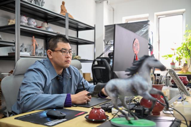 (260206) -- TIANJIN, Feb. 6, 2026 (Xinhua) -- An artist creates with an electronic pen on a computer at the Tianjin Clay Figurine Zhang Painted Sculpture Working Office in Tianjin, north China, Feb. 5, 2026. The Tianjin Clay Figurine Zhang Painted Sculpture Working Office has recently designed and created a series of painted sculptures themed on the Year of the Horse to greet the Chinese New Year. These artworks will be part of a Year of the Horse themed exhibition at the Tianjin Museum, which will be be open to the public free of charge during the Spring Festival. (Xinhua/Sun Fanyue)