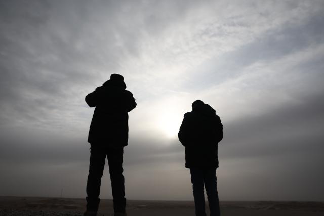 (260206) -- DUNHUANG, Feb. 6, 2026 (Xinhua) -- Staff members of the Yumenguan Conservation Station Sun Hailong (L) and Xiao Yonggang observe Przewalski's horses through binoculars at the Dunhuang West Lake National Nature Reserve in Dunhuang, northwest China's Gansu Province, Feb. 5, 2026.
  The Przewalski's horse, a globally endangered species under first-class national protection in China, was once extinct in the wild within the country. In 1985, China launched a reintroduction program, bringing the horses back from abroad for breeding. Within the 660,000-hectare Dunhuang West Lake National Nature Reserve, a conservation team works year-round as guardians of the Przewalski's horses. 
  Staff members conduct regular monitoring of the horses. They document foraging, drinking and population structure, while also patrolling the area and checking surrounding water resources. Additionally, they examine feces to assess the condition of the horses. After 40 years of reintroduction and conservation, the Przewalski's horse population in this reserve has grown to approximately 200, successfully transitioning from captive to natural breeding. 
  "Watching the horses running over the desert and grasslands makes our efforts worthwhile," said Wu Xingdong, head of the Yumenguan Conservation Station at the West Lake Reserve. (Xinhua/Chen Bin)