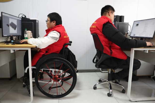 (260206) -- LANZHOU, Feb. 6, 2026 (Xinhua) -- AI training engineer Li Weiming (L) performs data annotation at a workshop for people with physical disabilities in Lanzhou, northwest China's Gansu Province, Jan. 14, 2026. TO WO WITH "Feature: AI creates jobs for people with disabilities amid China's tech drive" (Xinhua/Chen Bin)
