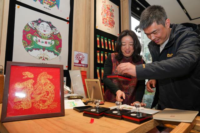 (260206) -- NANJING, Feb. 6, 2026 (Xinhua) -- People get special stamps at a store selling Taohuawu woodblock New Year prints in Suzhou, east China's Jiangsu Province, Feb. 5, 2026.
  Suzhou has a time-honored tradition of displaying New Year prints during the Spring Festival. Taohuawu woodblock New Year prints, named after their widespread popularity on Suzhou's Taohuawu Street in ancient times, boast a history of over 400 years. Their crafting technique traces back to the woodblock printing methods of the Song Dynasty (960-1279). Featuring a diverse range of themes, these prints not only express people's best wishes for the new year but also mirror the evolving changes in society. 
   With the Spring Festival approaching, Taohuawu woodblock New Year prints have been updated with fresh designs featuring the Year of the Horse elements. An exhibition of these prints is also being held at the Suzhou Art Museum. Meanwhile people can experience the prints making process in person and purchase cultural and creative products at a promotion center of Taohuawu woodblock New Year prints. (Xinhua/Li Bo)