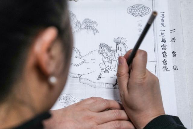 (260206) -- NANJING, Feb. 6, 2026 (Xinhua) -- Qiao Lanrong, an inheritor of Taohuawu woodblock New Year prints, designs patterns for a New Year print at her studio in Suzhou, east China's Jiangsu Province, Feb. 5, 2026.
  Suzhou has a time-honored tradition of displaying New Year prints during the Spring Festival. Taohuawu woodblock New Year prints, named after their widespread popularity on Suzhou's Taohuawu Street in ancient times, boast a history of over 400 years. Their crafting technique traces back to the woodblock printing methods of the Song Dynasty (960-1279). Featuring a diverse range of themes, these prints not only express people's best wishes for the new year but also mirror the evolving changes in society. 
   With the Spring Festival approaching, Taohuawu woodblock New Year prints have been updated with fresh designs featuring the Year of the Horse elements. An exhibition of these prints is also being held at the Suzhou Art Museum. Meanwhile people can experience the prints making process in person and purchase cultural and creative products at a promotion center of Taohuawu woodblock New Year prints. (Xinhua/Li Bo)