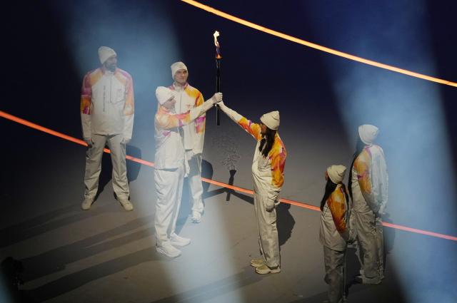 (260207) -- MILAN, Feb. 7, 2026 (Xinhua) -- Torchbearers pass the flame during the opening ceremony of the Milan-Cortina 2026 Olympic Winter Games at the San Siro Olympic Stadium in Milan, Italy, Feb. 6, 2026. (Xinhua/Xue Yuge)